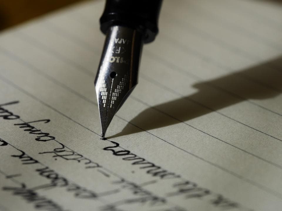 A fountain pen resting on handwritten lines