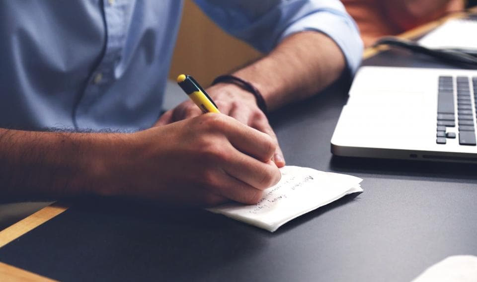 A hand signing a printed agreement with a pen