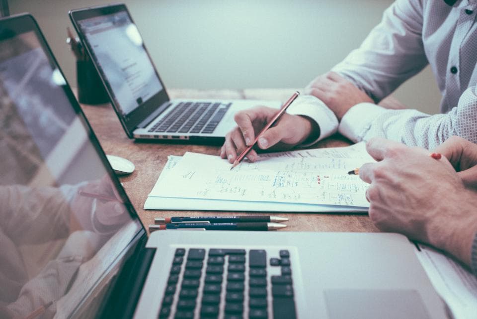 The paralegal's hands at a laptop with papers beside it